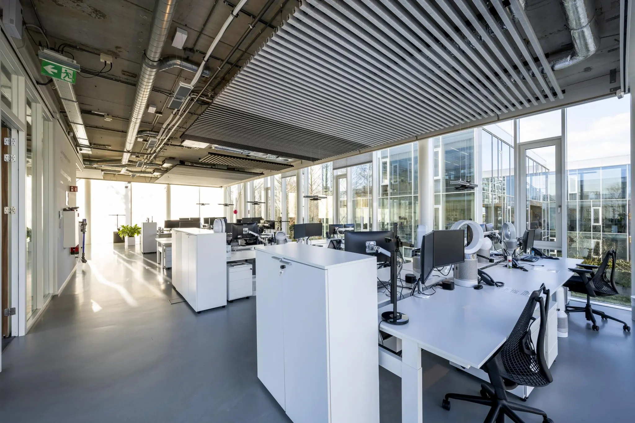 Moderne open kantoorruimte aan de Fred. Roeskestraat met grote ramen, werkplekken en industrieel plafondontwerp.